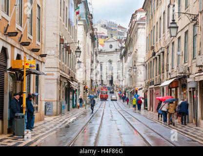 Das Lissabon Stadtbild mit roten Straßenbahn auf Rua Vitor Cordon während des Regens. Menschen versuchen zu verstecken vor dem Regen und gehen Sie zu den Geschäften Stockfoto