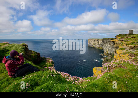 Weibliche Vogelbeobachter Marwick Head (RSPB) Seevogel-Kolonie mit dem Kitchener-Denkmal in der Ferne, Orkney Festland, Schottland. Stockfoto