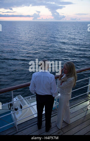 Ein paar beobachtet während einer Ostsee Kreuzfahrt einen nahenden Sonnenuntergang vom Deck der Windstar Cruises Segel-Cruiser Wind Surf. Stockfoto