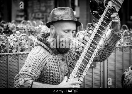 Straßenmusikanten ein Grand Pro Tun Sitar in Abington Street, Northampton Town Centre eine indische Instrument zu spielen. Stockfoto