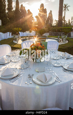 Gartentisch-Einstellung bei Hochzeitsfeier unter Sonnenuntergang Sonnenstrahlen Stockfoto