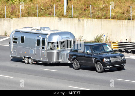 Fahrer und Beifahrer im Range Rover Auto abschleppen Airstream Wohnwagen UK M25 Autobahn entlangfahren verdeckt Nummernschild Stockfoto