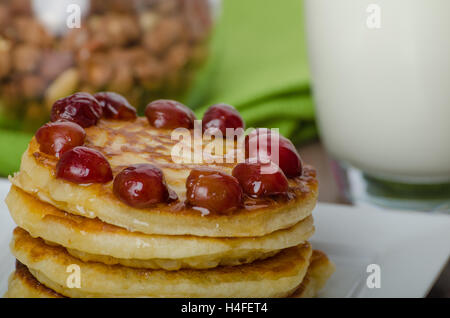 Nach Hause flauschige Pfannkuchen mit Kirschen Kirschen und Honig, Milch trinken Stockfoto