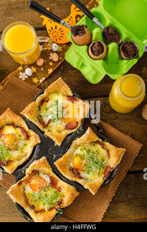Spiegeleier in Blätterteig in Schinken, überbacken mit Käse und garniert mit Microgreens, gefüllt mit frischer Saft aus Orangen und Eiern Stockfoto