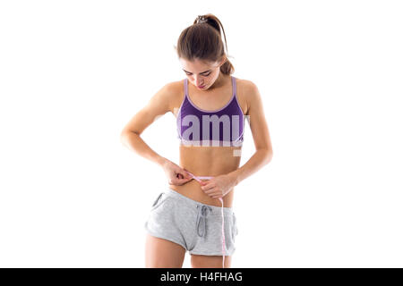 Sportliche Frau, die ihre Taille messen Stockfoto