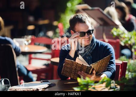 Cooler junger Mann in Sonnenbrille Bestellung etwas in einem Straßencafé Stockfoto