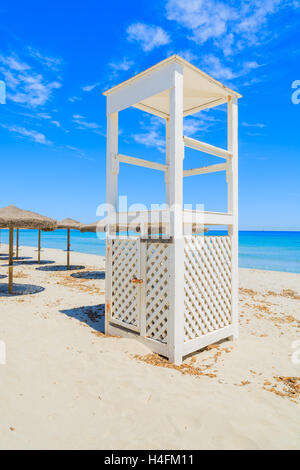 Weiße Holz Rettungsschwimmer und Liegestühle mit Sonnenschirmen am weißen Sandstrand in Villasimius Dorf am Meer, Insel Sardinien, Italien Stockfoto