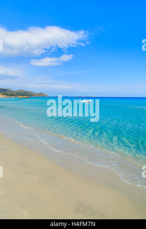 Weißes Boot in Ferne auf wunderschönen türkisfarbenen Meerwasser von Porto Giunco Beach, Insel Sardinien, Italien Stockfoto