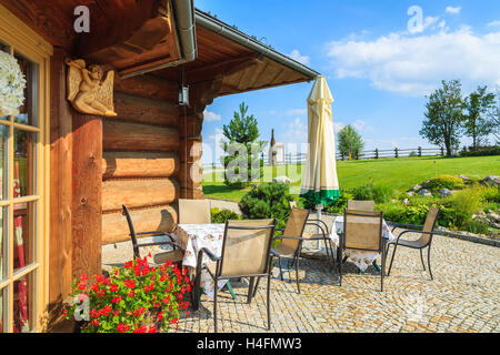 Dorf in der Nähe von Krakau, Polen - 9. August 2014: Terrasse mit Stühlen und Tischen der traditionellen Restaurantgebäude an sonnigen Sommertag. Berg-Stil-Architektur ist sehr beliebt im Süden Polens. Stockfoto