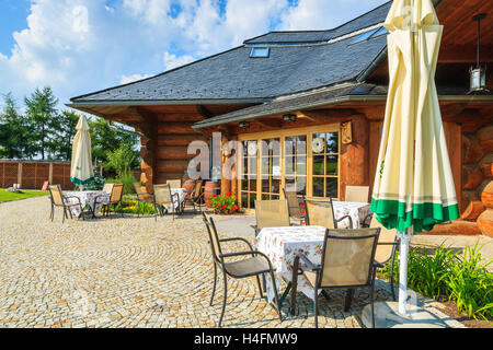 Dorf in der Nähe von Krakau, Polen - 9. August 2014: Terrasse mit Stühlen und Tischen der traditionellen Restaurantgebäude an sonnigen Sommertag. Berg-Stil-Architektur ist sehr beliebt im Süden Polens. Stockfoto