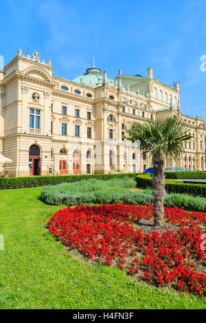 Rote Blumen mit Palme vor Slowackiego Theatergebäude in Krakau, Polen Stockfoto