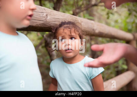 Porträt von unschuldigen niedliche kleine Mädchen sah ihre Schwester und Mutter mit Augen voller Angst im Park gegen Bäume Stockfoto