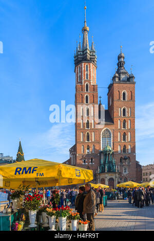 Krakau, Polen - 13. Dezember 2014: Touristen von Blumen am Main Markt Platz von Krakau mit Marienkirche im Hintergrund. Jedes Jahr findet ein Weihnachtsmarkt in der Altstadt von Krakau, Polen. Stockfoto