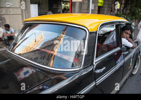 Traditionell gelb und Schwarz Ambassador Taxi im Zentrum von Mumbai, Bombay mit Reflexion der indischen Börse. Indien. Stockfoto