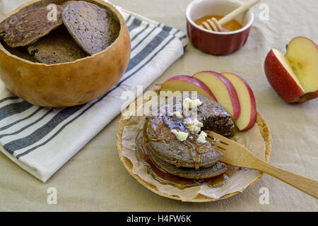 Rustikale Mahlzeit von Buchweizen Pfannkuchen Teller und Schale aus Kürbissen auf Blume Sac Tischdecke, begleitet von Ahornsirup Stockfoto