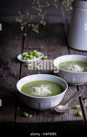 Erbsen und Bohnen Creme Suppe in Keramikschalen mit Parmesan auf Holztisch Stockfoto