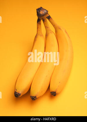 Drei frische Bananen auf gelbem Hintergrund Stockfoto