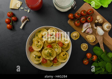 Hausgemachte Tortellini gefüllt, Pilze und Tomaten mit Feta-Käse Stockfoto