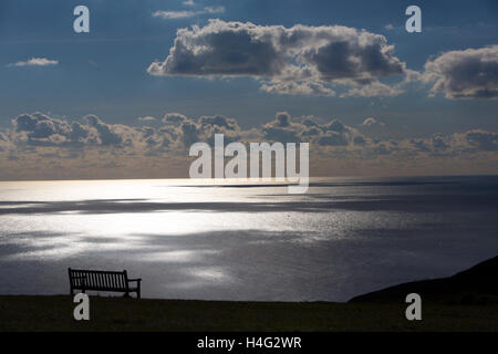 Kreide Klippen einsame leere einsame Einsamkeit Sonnenlicht auf Wolken Reflexionen Meerblick in Richtung Frankreich Ruhestand Sitzbank Sitz Ferienpark leer mit Blick auf Meer Tennyson Down Isle Of Wight UK Silhouette Liebe küssen Wanderweg zu Fuß Wanderung Wandern Wanderer Silber Schatten Lichtstrahlen Stockfoto