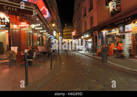 PARIS, Frankreich 13. August 2016: ein Blick auf eine Straße in Paris bei Nacht zeigt die Bewegungsunschärfe von Menschen und Restaurants, Cafés und andere Geschäfte Stockfoto
