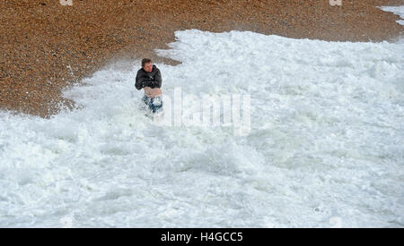 Brighton, Sussex UK 16. Oktober 2016 - ein junger Mann geht für einen gewagten paddeln in rauer See auf Brighton Beach als windigem Wetter entlang der südlichen Küste England fegt heute Credit: Simon Dack/Alamy Live News Stockfoto