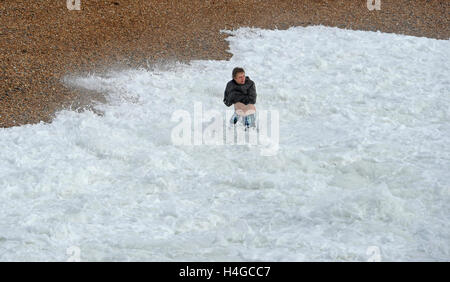 Brighton, Sussex UK 16. Oktober 2016 - ein junger Mann geht für einen gewagten paddeln in rauer See auf Brighton Beach als windigem Wetter entlang der südlichen Küste England fegt heute Credit: Simon Dack/Alamy Live News Stockfoto