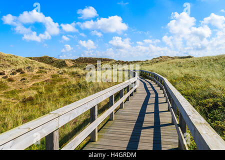 Holzsteg zum Strand zwischen den Sanddünen und sonnigen blauen Himmel mit weißen Wolken, Insel Sylt, Deutschland Stockfoto