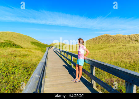 Junge Frau touristischen stehend auf Holzsteg zum Strand unter den Dünen auf der Insel Sylt, Deutschland Stockfoto