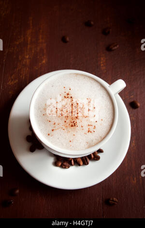 Tasse Cappuccino Kaffee mit Kakao Topping über rustikale Holz dunkel Stockfoto