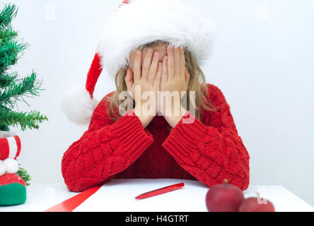 Traurige Mädchen im roten Hut einen Brief an den Weihnachtsmann schreiben. Stockfoto