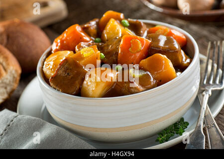 Eine leckere Schale mit reichhaltigen und herzhaften Rindfleisch-Eintopf mit Kartoffeln, Rüben, Karotten, Sellerie und Erbsen. Stockfoto