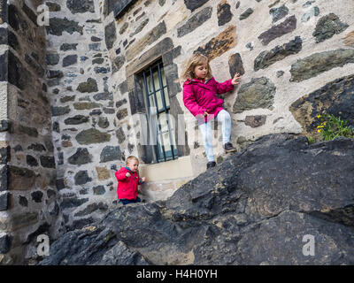 Kleine Jungen und Mädchen, Kletterfelsen, an der Wand auf das kleine Schloss in Calton Hill in Edinburgh, Schottland Stockfoto