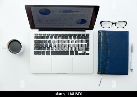 Weißer Schreibtisch mit Brille, Laptop, Kaffee und notebook Stockfoto