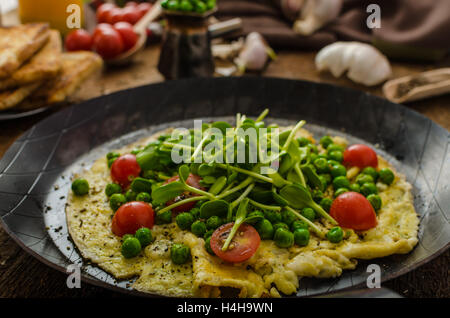 Gesunden Omelette mit Gemüse - Erbsen und Sonnenblumen Microgreens toast Cherry-Tomaten Stockfoto