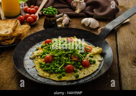 Gesunden Omelette mit Gemüse - Erbsen und Sonnenblumen Microgreens toast Cherry-Tomaten Stockfoto