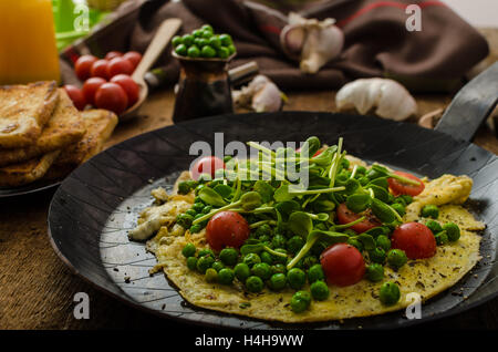 Gesunden Omelette mit Gemüse - Erbsen und Sonnenblumen Microgreens toast Cherry-Tomaten Stockfoto