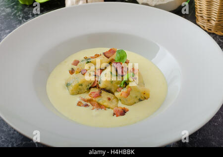 Spinat-Gnocchi mit Parmesan-Sauce, garniert mit Speck, reinigen dienen, Zutaten im Hintergrund Stockfoto