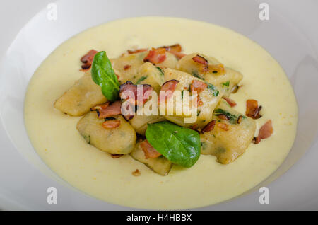 Spinat-Gnocchi mit Parmesan-Sauce, garniert mit Speck, reinigen dienen, Zutaten im Hintergrund Stockfoto