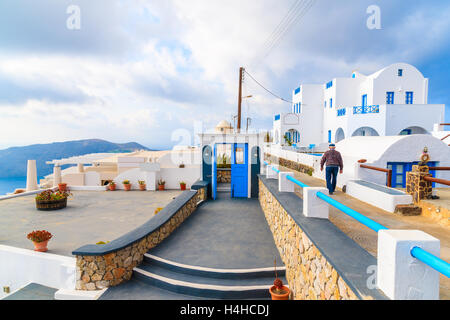 Unbekannten griechischen Alter Mann zu Fuß in Imerovigli Dorf an einem bewölkten Tag mit dramatischer Himmel, Santorin, Griechenland Stockfoto