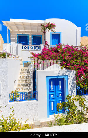 Typischen weißes-blaues griechisches Haus verziert mit roten Blumen im Dorf Oia auf Santorin, Griechenland Stockfoto