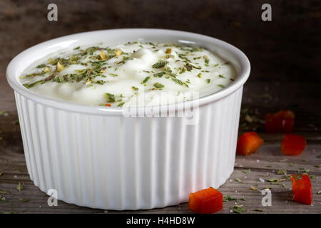 Sauce aus Joghurt und Kräutern in eine weiße Keramikschale auf einem Holztisch Stockfoto