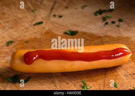 Gekochte Wurst mit Ketchup und Kräuter auf hölzernen Hintergrund Stockfoto