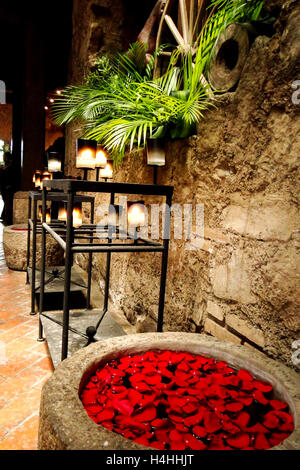 Kandelaber der brennenden Kerzen in einem Schloss voller Pflanzen und Rosenblüten Bade Stockfoto