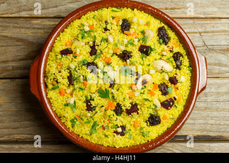 Couscous in einem Tontopf auf einem Holztisch Stockfoto