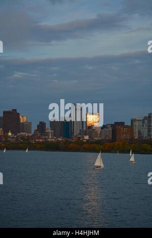 Ein Blick auf die Skyline der Innenstadt Boston bei Sonnenuntergang von Cambridge über den Charles River mit Segelbooten. Stockfoto