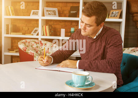 Mann hält Bleistift und schreiben auf dem Papier im Tagebuch Stockfoto