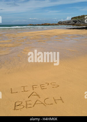 Die Worte "Das Leben ist ein Strand" in goldenen gelben Sand der abgelegenen schottischen Strand geschrieben. Stockfoto