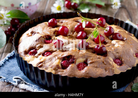 Hausgemachter Schokoladenkuchen mit Kirschen und frischen Beeren auf dem Holztisch. Stockfoto