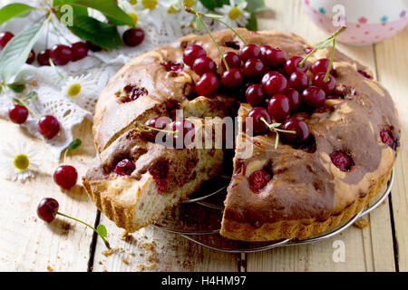 Hausgemachter Schokoladenkuchen mit Kirschen und frischen Beeren im rustikalen Stil. Stockfoto