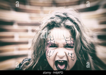 Gruselige kleine Mädchen in schwarz Halloween-Kostüm und lackierten Webs auf Gesicht mit offenem Mund. Stockfoto